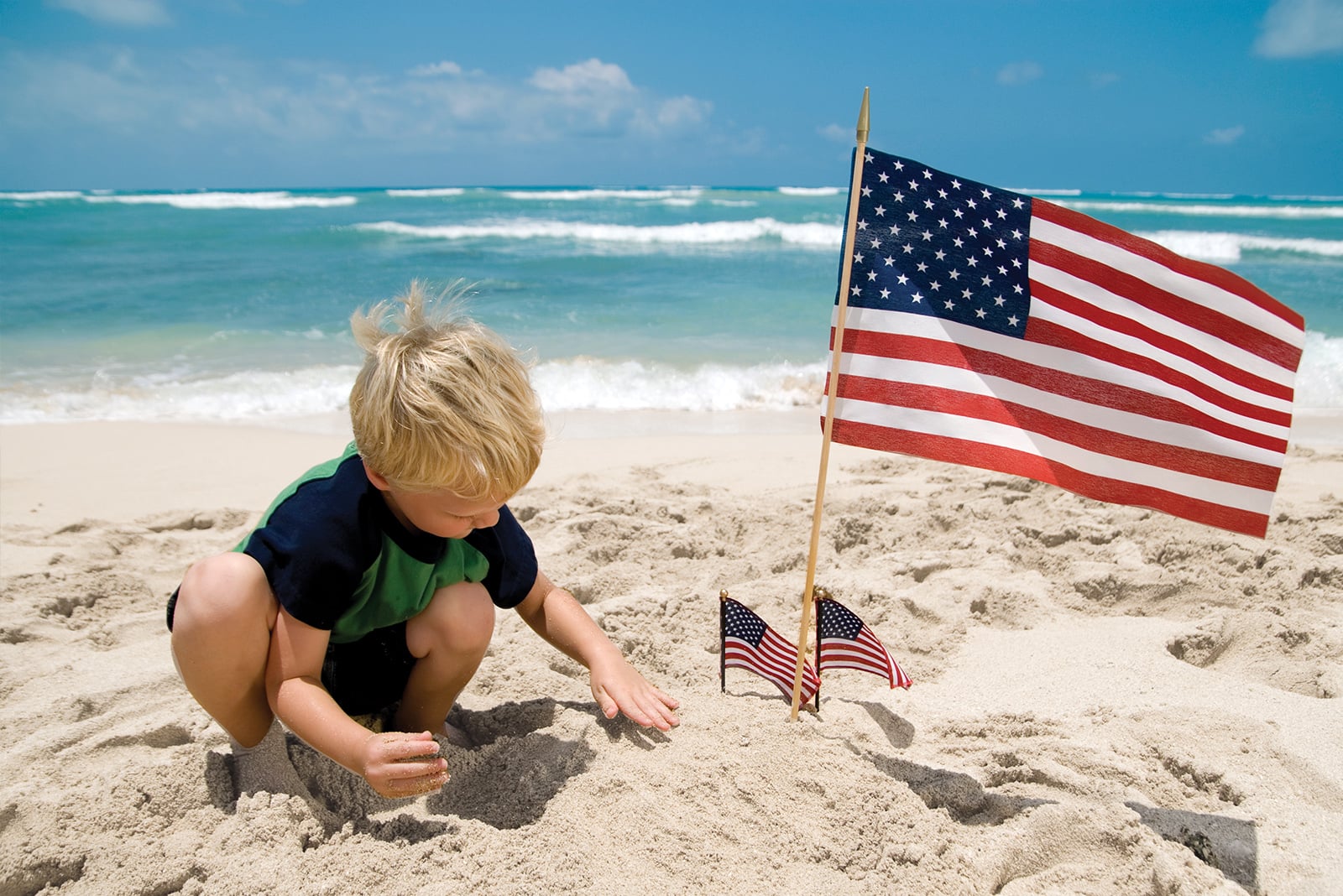 Child playing in sand with American flags