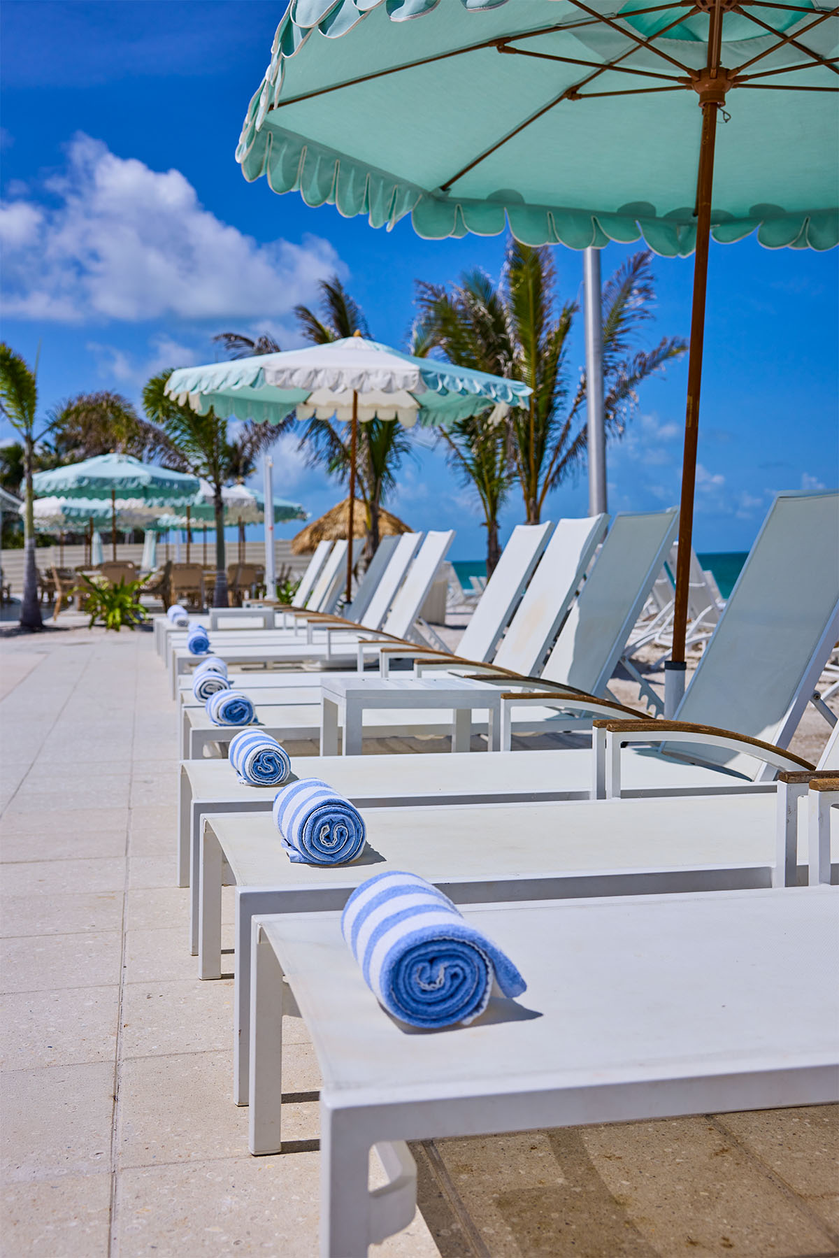Beach club chairs in line with umbrellas and towels ready for guests.