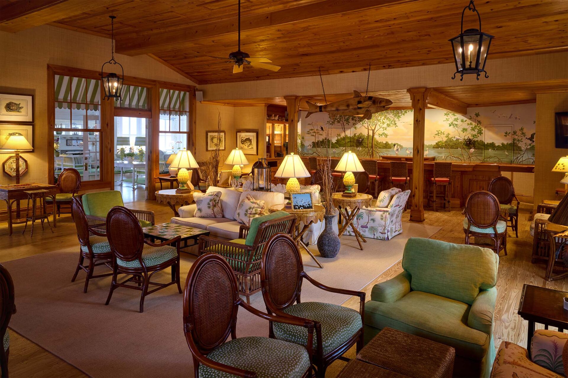 Rustic bar with brown wicker and wood, with a wooden fish hanging in front of bar.