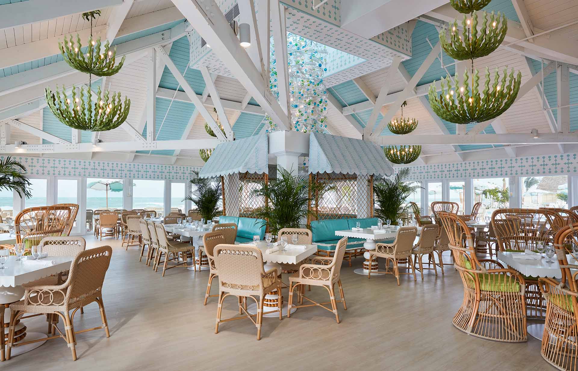 The classic wicker furniture of the beach club's dining area, featuring seaweed-themed chandeliers