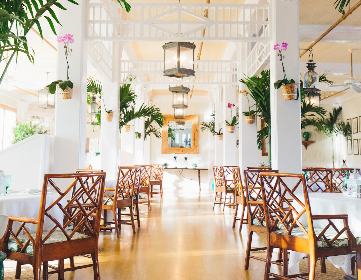 The center aisle of the main dining room, flanked by vintage tables and chairs and topped by a long row of wrought iron lanterns