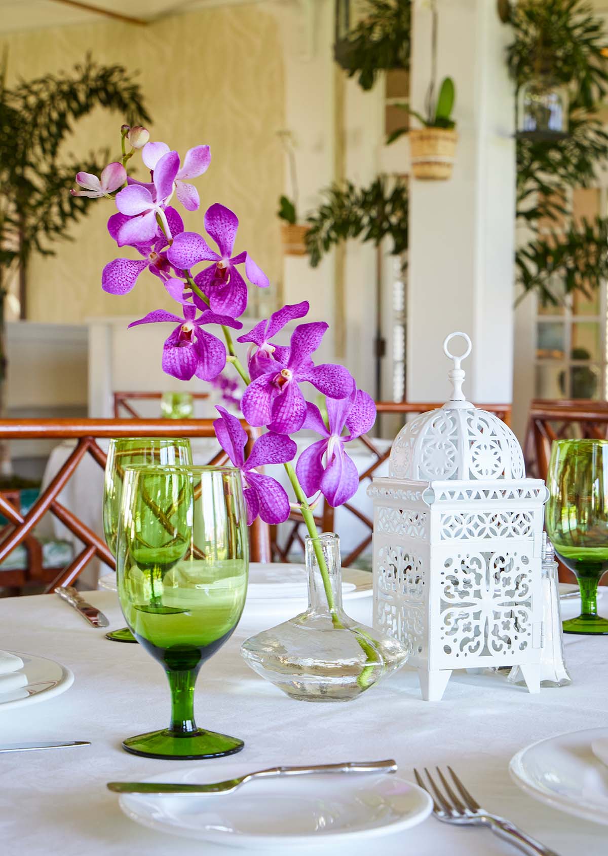 Tabletop place setting includes an intricate, white Moroccan lantern beside a lavender iris in a glass vase