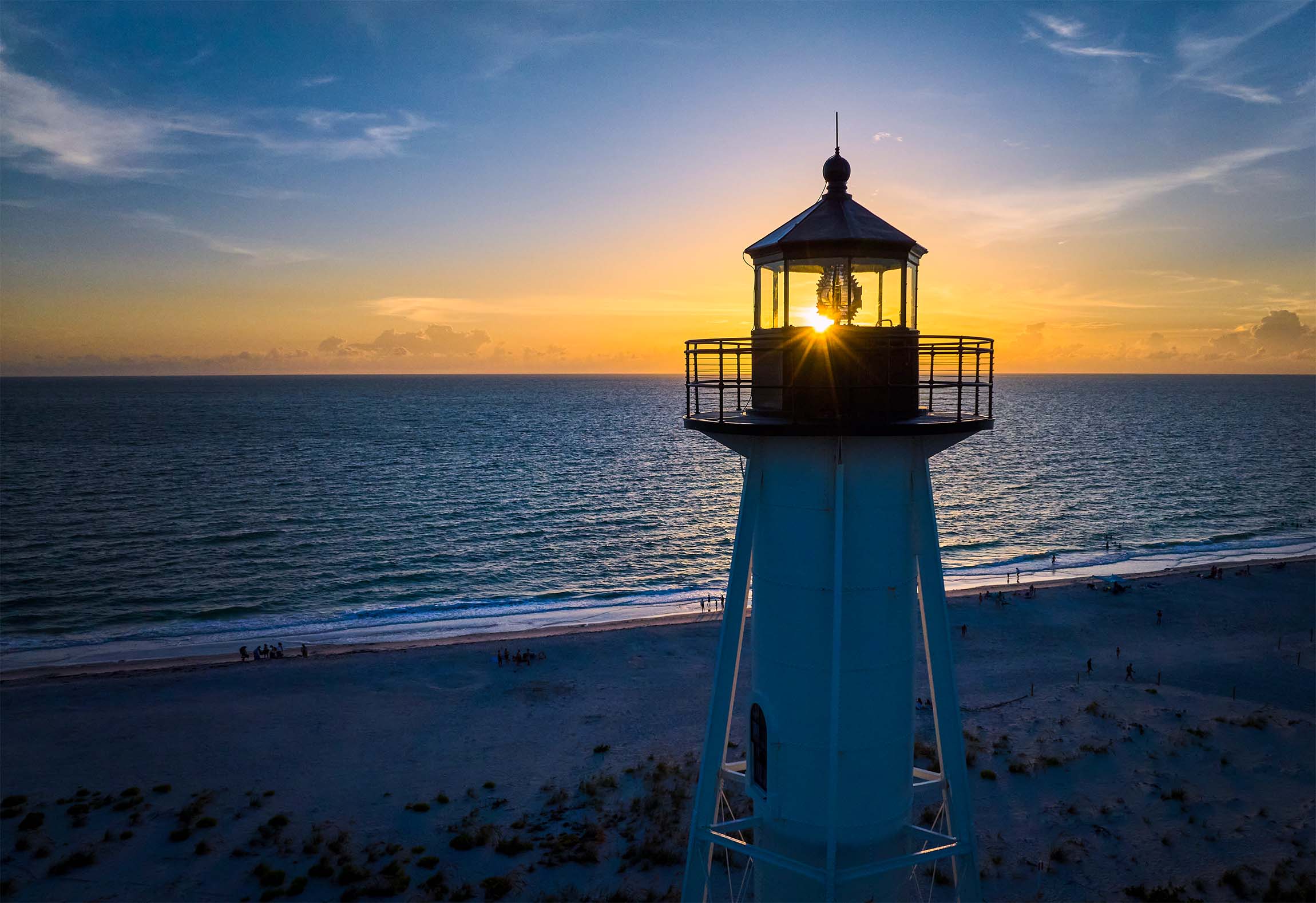 Lighthouse on beach with sunset.