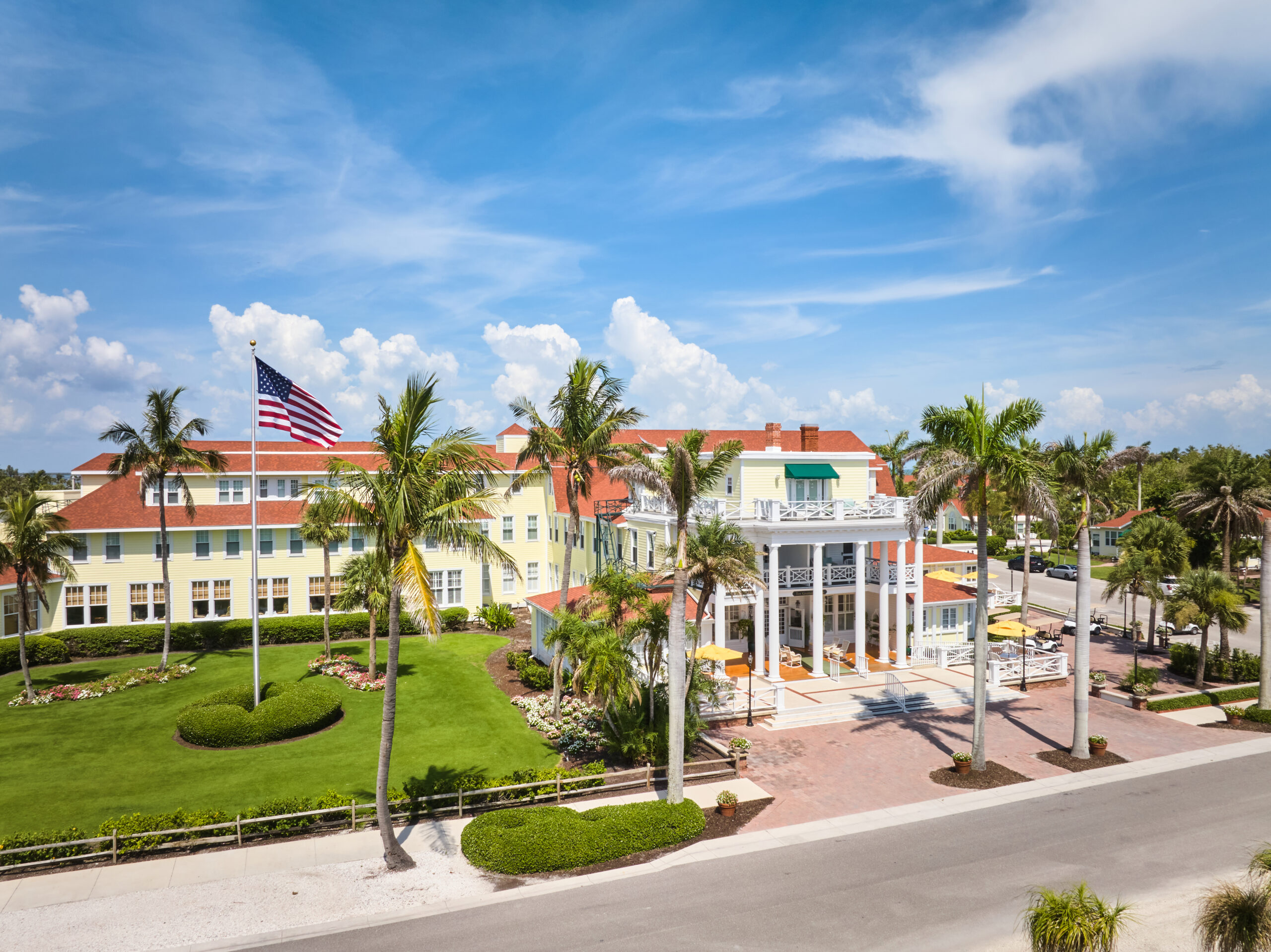 Yellow wooden hotel with American flag and palm trees.