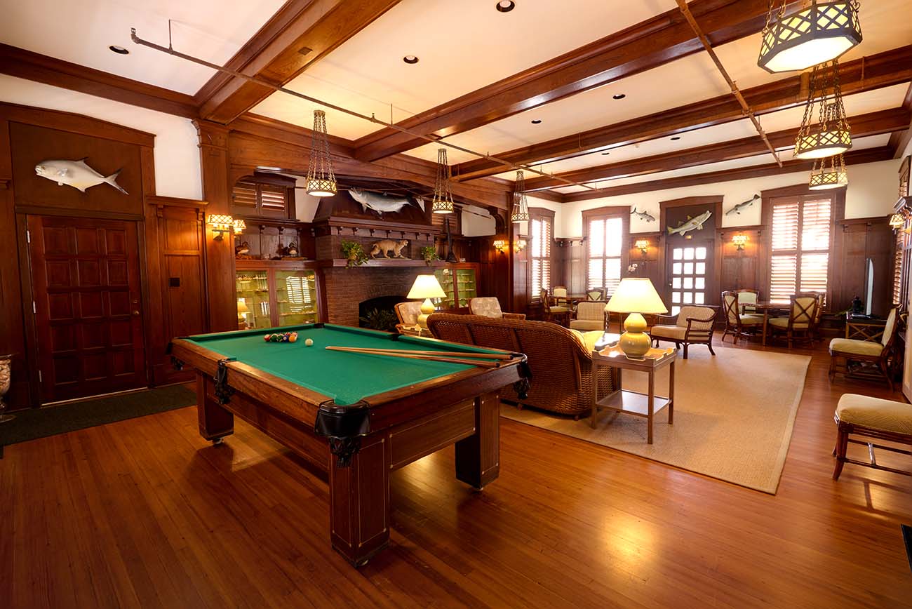 Rustic wood covered room with pool table and fish trophies on wall.