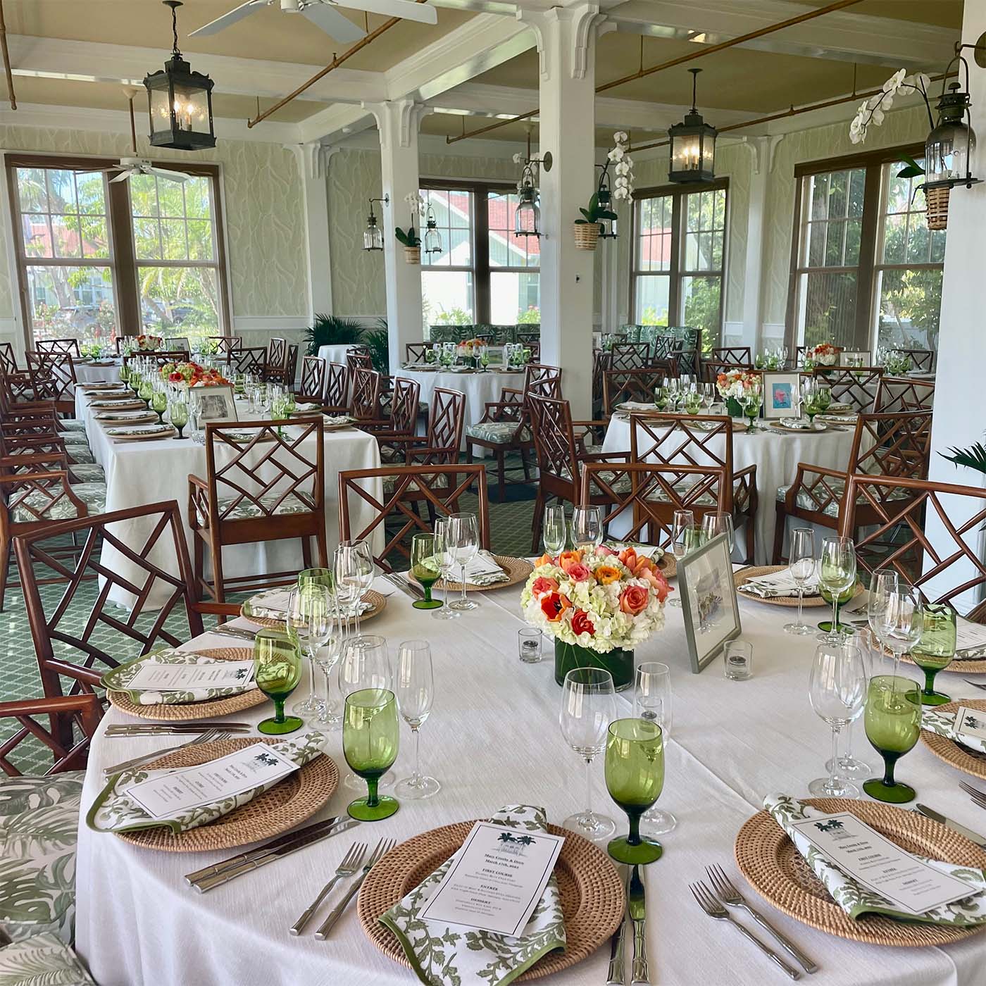 White table cloth table setting with green glasses and rattan chargers.