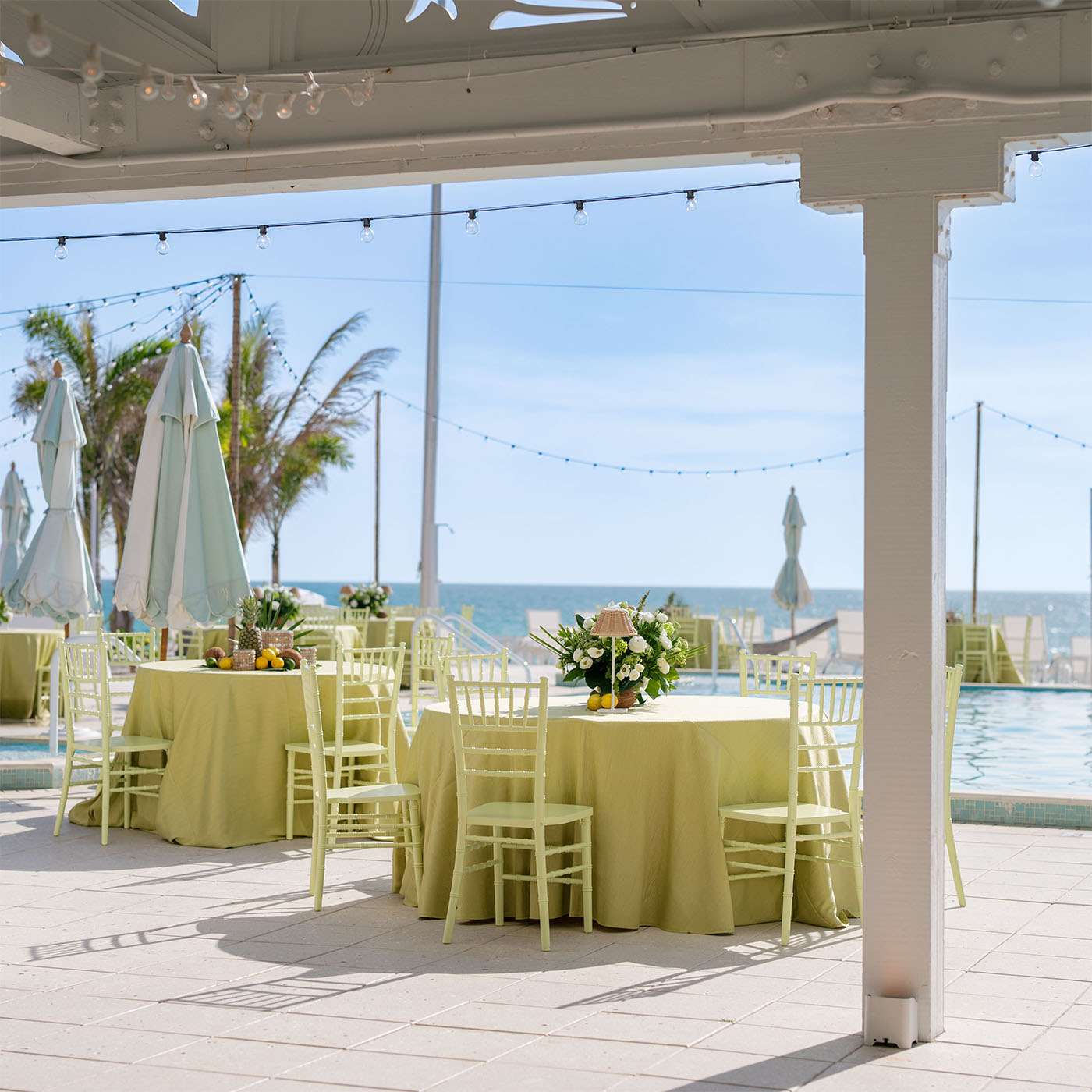 Chairs set for event, pool and ocean in background