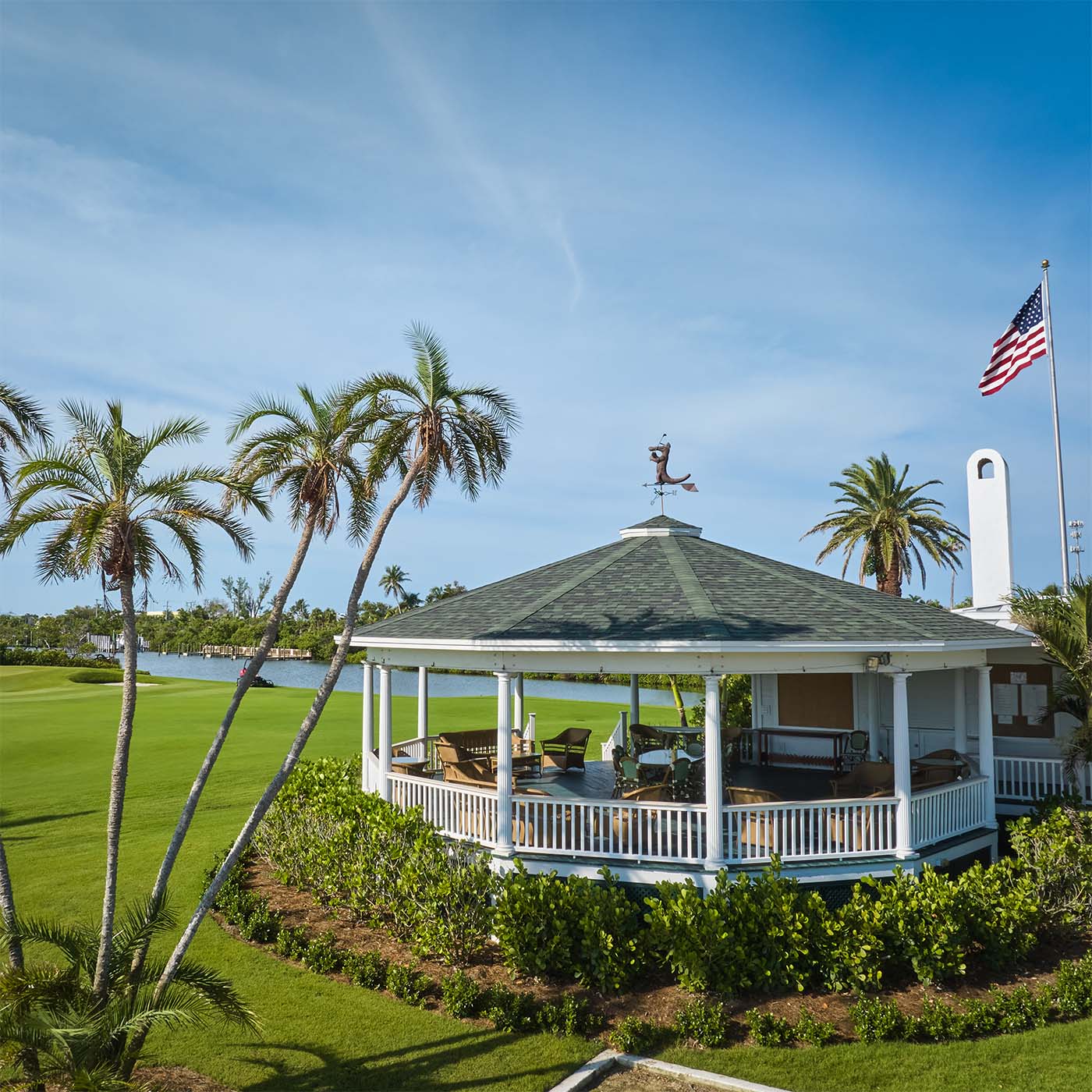 Gazebo with palm trees and American flag in front of water