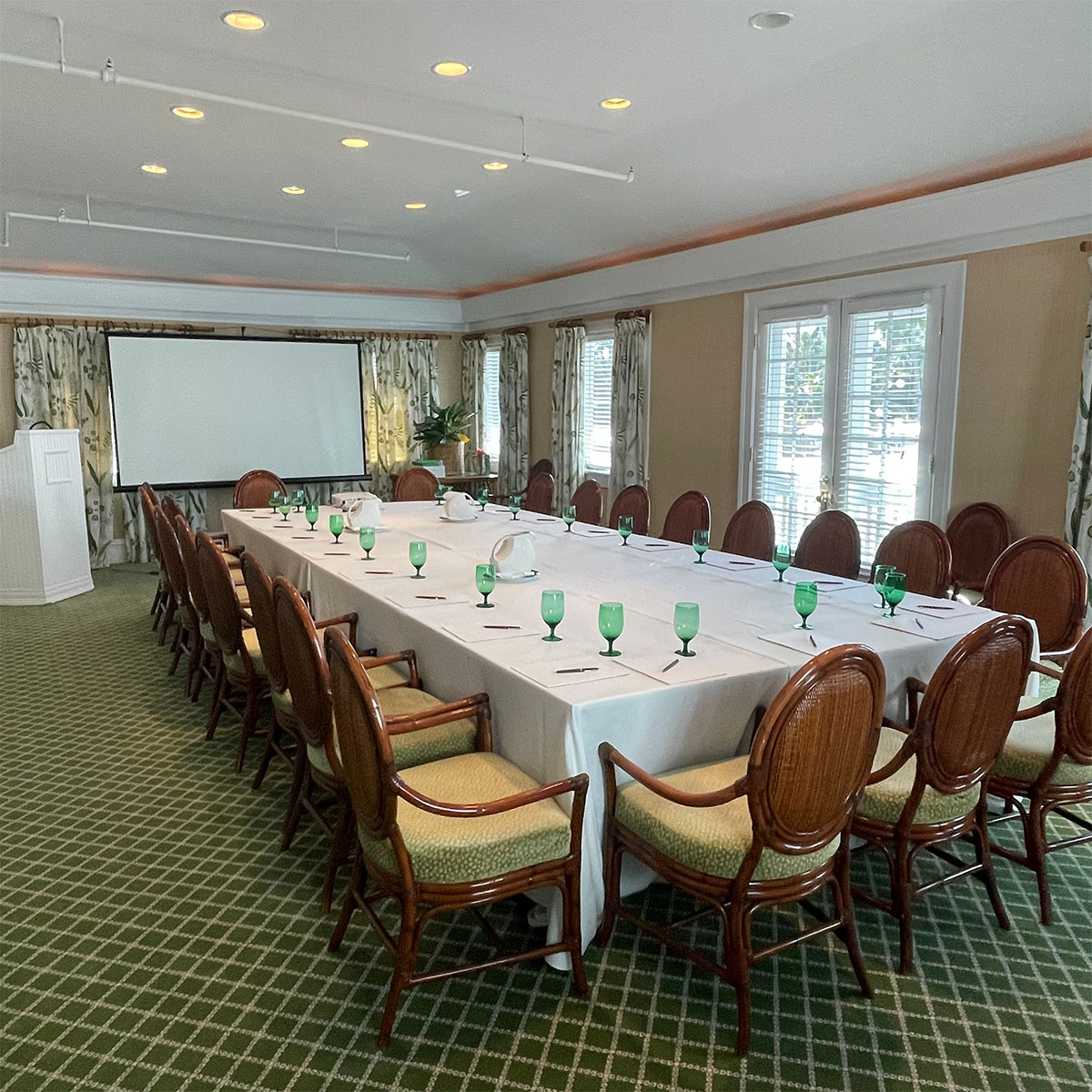 Room with long horizontal conference table and projector screen.